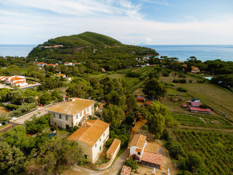 Vista aérea de Camping Casa dei Prati, un parque vacacional en la Toscana, Italia, con mar y colinas verdes.