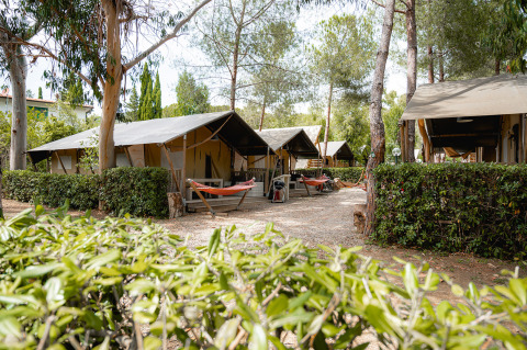 Luxury tents and hammocks at Camping Casa dei Prati holiday park in Tuscany, Italy, surrounded by trees.