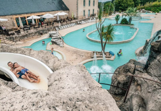 En vandrutsjebane ved svømmebassiner og palmer på Camping Castel L'Orangerie de Lanniron i Bretagne, Frankrig.