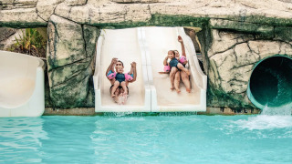 Kinder fahren gemeinsam auf einer Doppelwasserrutsche im Camping Castel L'Orangerie de Lanniron in der Bretagne.