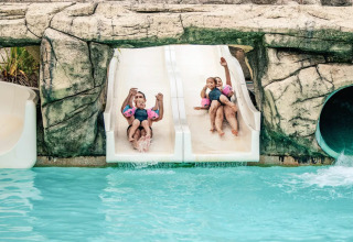 Niños disfrutando en un tobogán doble en la piscina de Camping Castel L'Orangerie de Lanniron, Bretaña, Francia.