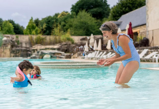 Una mujer y dos niños juegan en la piscina del Camping Castel L'Orangerie de Lanniron, Bretaña, Francia.