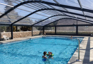 Indoor swimming pool with transparent roof and guests at Camping Castel L'Orangerie de Lanniron, Brittany, France