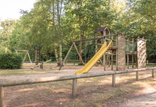 Speelplein met houten structuren en gele glijbaan op Camping Castel L'Orangerie de Lanniron, Bretagne, Frankrijk.