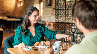 Eine Frau und ein Mann frühstücken gemeinsam in einem gemütlichen Restaurant des Camping Castel L'Orangerie de Lanniron.