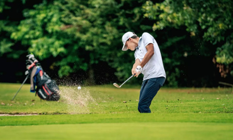 A golfer hits a ball from a sand bunker at Camping Castel L'Orangerie de Lanniron in Brittany, France.