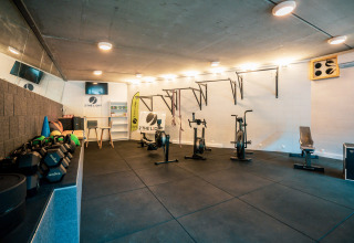 Indendørs fitnesscenter med træningsudstyr på Camping Castel L'Orangerie de Lanniron i Bretagne, Frankrig.