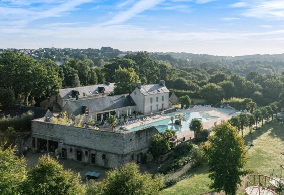Luftfoto af Camping Castel L'Orangerie de Lanniron i Bretagne, Frankrig, med swimmingpool og grønne omgivelser.
