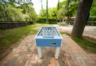 Voetbaltafel buiten bij Camping Colleverde, omgeven door bomen en groen in de Toscane, Italië.