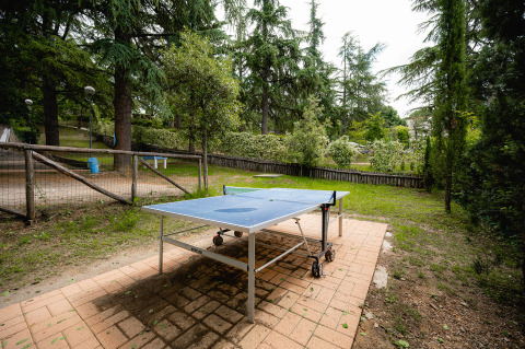 Außentischtennisplatte auf Terrasse, umgeben von Bäumen im Ferienpark Camping Colleverde, Toskana, Italien.