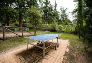 Außentischtennisplatte auf Terrasse, umgeben von Bäumen im Ferienpark Camping Colleverde, Toskana, Italien.