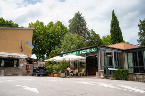 Camping Colleverde parque vacacional en la Toscana, Italia, con recepción y RISTORANTE PIZZERIA rodeado de árboles.