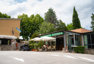 Camping Colleverde vakantiepark in Toscane, Italië, met receptie en RISTORANTE PIZZERIA tussen de bomen.