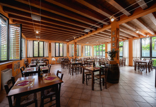 Eetruimte op Camping Colleverde in Toscane met houten tafels, open ramen en een gezellige, warme sfeer.