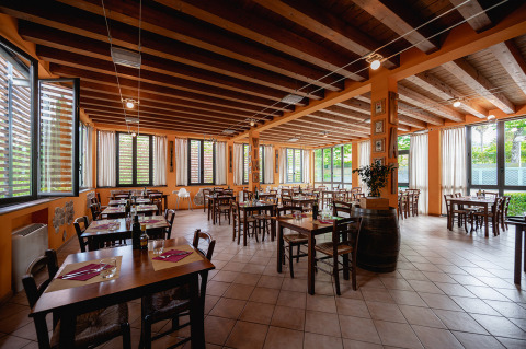 Eetruimte op Camping Colleverde in Toscane met houten tafels, open ramen en een gezellige, warme sfeer.