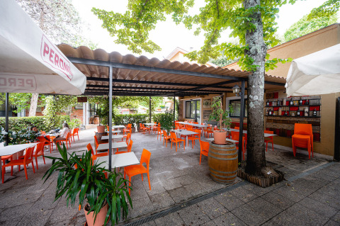 Terrazza esterna con sedie arancioni al Camping Colleverde, un villaggio turistico in Toscana, Italia.