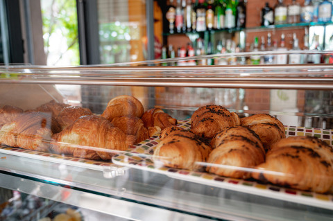 Cruasanes recién horneados expuestos en una vitrina de una cafetería en Camping Colleverde, Toscana, Italia.