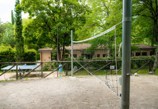 Udendørs volleybane og bordtennisbord på Camping Colleverde i Toscana, Italien, omgivet af grønne træer.