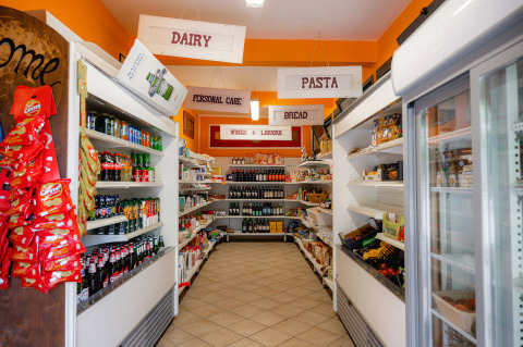 Pequeña tienda en Camping Colleverde, Toscana, con estantes llenos de alimentos y bebidas.