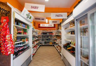 Kleine supermarkt op Camping Colleverde, Toscane, met rekken vol voeding en drank.