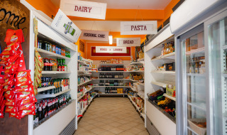 Kleiner Supermarkt im Camping Colleverde, Toskana, mit Regalen voller Lebensmittel und Getränken.