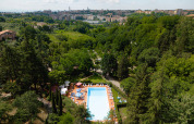 Luftfoto af swimmingpool omgivet af træer på Camping Colleverde, med udsigt over Siena, Toscana, Italien.