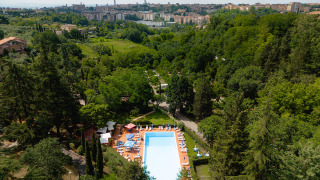 Luchtfoto van een zwembad op Camping Colleverde, omgeven door bomen met uitzicht op Siena in Toscane.