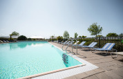 Outdoor swimming pool with sun loungers and umbrellas at Camping de Molenhoek holiday park in Zeeland, Netherlands.