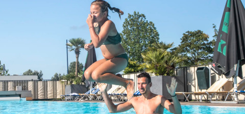 Un uomo solleva una ragazza in costume da bagno fuori dalla piscina a Camping de Molenhoek, Zelanda, Paesi Bassi.