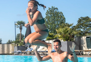 Un uomo solleva una ragazza in costume da bagno fuori dalla piscina a Camping de Molenhoek, Zelanda, Paesi Bassi.