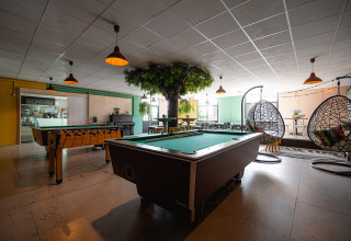 Salle de loisirs au Camping de Molenhoek avec billard, baby-foot, coin salon et fauteuils suspendus.