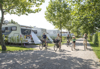 Famiglie in bicicletta lungo un vialetto accanto a roulotte al Camping de Molenhoek, parco vacanze in Zeeland, Olanda.