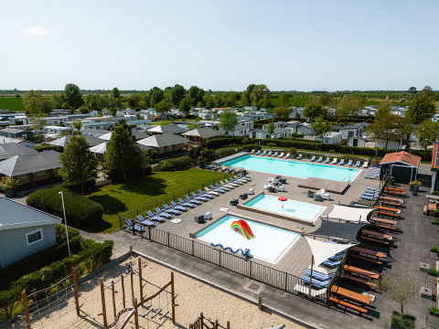 Vista aerea di Camping de Molenhoek a Zeeland, Paesi Bassi, con piscine, lettini e case mobili.