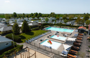 Vista aerea di Camping de Molenhoek a Zeeland, Paesi Bassi, con piscine, lettini e case mobili.