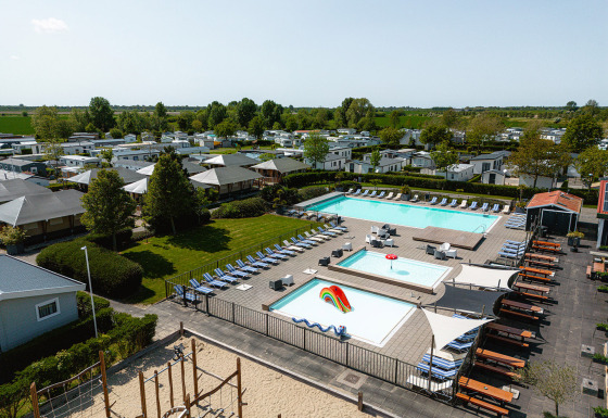 Vista aerea di Camping de Molenhoek a Zeeland, Paesi Bassi, con piscine, lettini e case mobili.