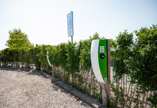 Electric car charging stations at a parking area lined with hedges at Camping de Molenhoek in Zeeland, Netherlands.
