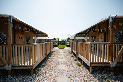 Houten chalets met veranda’s op Camping de Molenhoek vakantiepark in Zeeland, Nederland, op een zonnige dag.