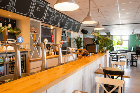 Bright, modern bar area with beer taps and seating at Camping de Molenhoek holiday park in Zeeland, Netherlands.