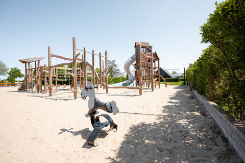 Parque infantil de arena y estructuras de madera en Camping de Molenhoek, Zeeland, Países Bajos, en día soleado.