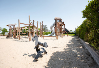 Aire de jeux en sable avec structures en bois au Camping de Molenhoek, à Zeeland, Pays-Bas, sous un ciel clair.