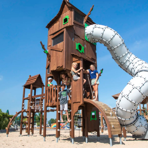 Bambini giocano in un grande parco giochi con torre e scivolo al Camping de Molenhoek, Zelanda, Paesi Bassi.