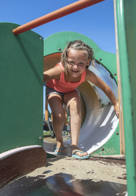 Girl playing on the playground at Camping de Molenhoek, a holiday park in Zeeland, Netherlands, on a sunny day.