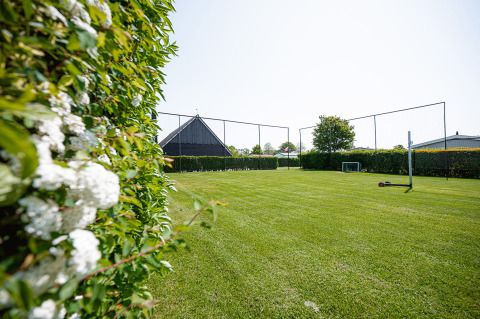 Campo deportivo de césped en Camping de Molenhoek, rodeado de setos y redes, en Zeeland, Países Bajos.