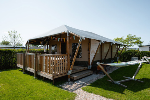 Tenda safari di lusso con veranda e amaca al Camping de Molenhoek, parco vacanze in Zeeland, Paesi Bassi.