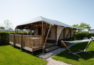 Luxury safari tent cabin with porch and hammock at Camping de Molenhoek holiday park in Zeeland, Netherlands.