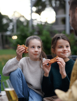 Familia disfruta de un picnic con comida y bebida en la hierba de un parque de vacaciones con glamping.