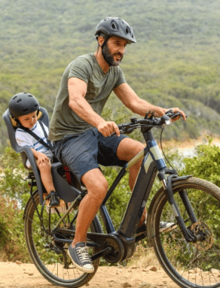 Een man fietst met een kind in een stoeltje door het natuurrijke gebied rond Stolwijk, Zuid-Holland.