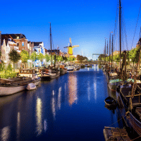 Avondbeeld van een kanaal met boten, historische huizen en molen nabij Stolwijk, Zuid-Holland, Nederland.