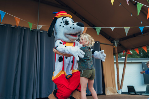 Niño abrazando a una mascota dálmata en el escenario con banderines en Camping de Papillon, Overijssel, Países Bajos.