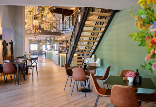 Modern café-interieur in Camping de Papillon, vakantiedomein in Overijssel, Nederland, met trap.